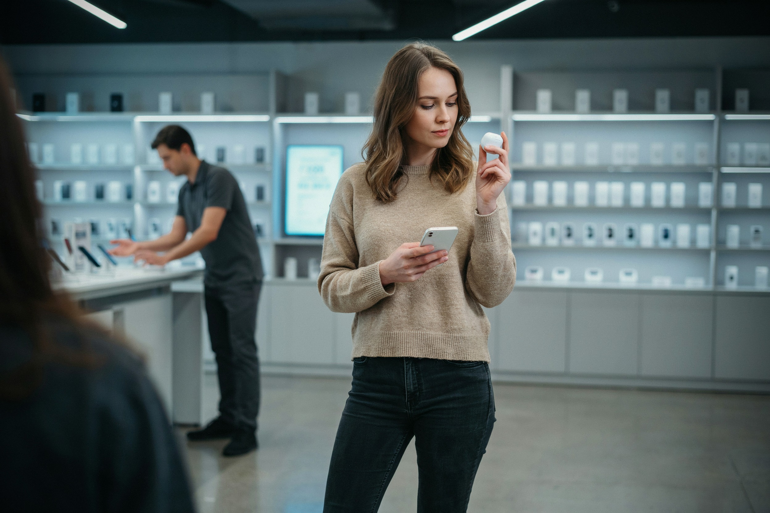 Client consultant un iPhone et des AirPods dans une boutique moderne